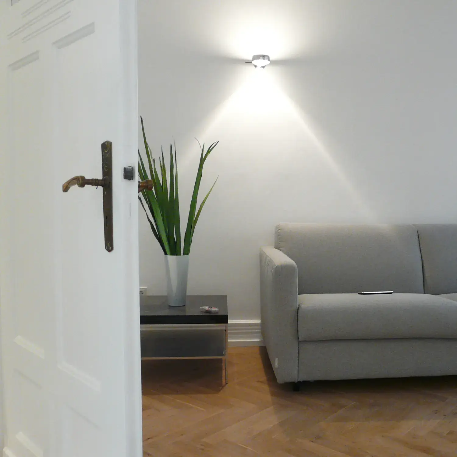Helles Wohnzimmer mit weiß gestrichenen Wänden, natürlichem Holzboden und dezenter Beleuchtung als Beispiel für gesundes und schadstoffarmes Wohnen beim Fachbetrieb für Gesundes Wohnen in Düsseldorf von Malermeister Kleinau