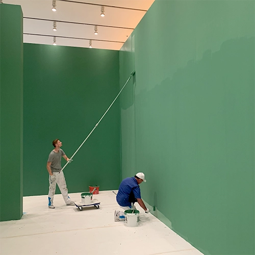 Malerarbeiten an hohen Ausstellungswänden während des Ausstellungsaufbaus im Museum